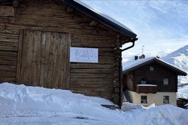 Drewniana chata na zaśnieżonym zboczu obok innej górskiej chaty.