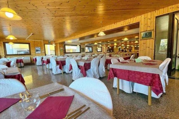 Przestronna restauracja ze stołami z białymi i czerwonymi obrusami.